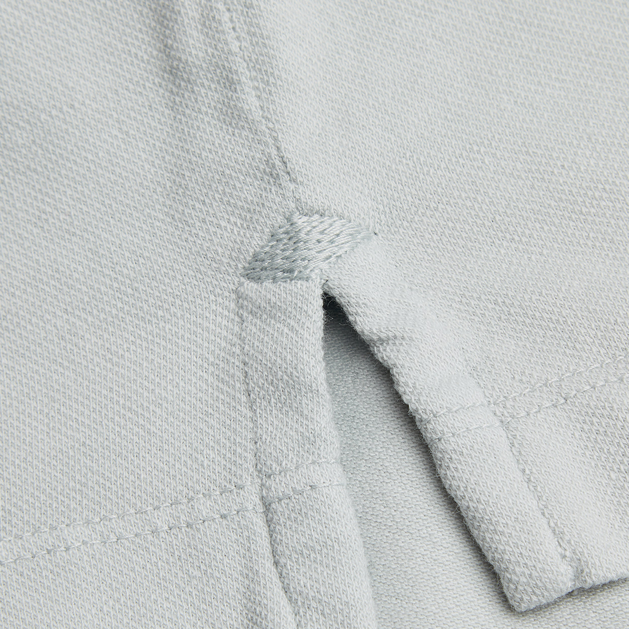 Dettaglio tessuto micro piquet tinta in capo, cuciture precise e finiture premium per abbigliamento uomo